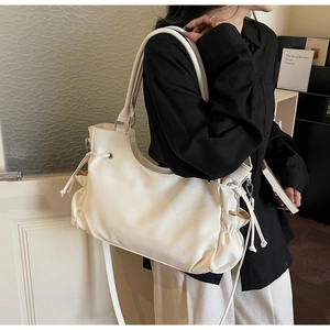 Detail view of large cream tote bag showing drawstring sides and smooth leather texture