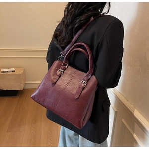 Mannequin portant un sac vintage bordeaux en cuir à texture litchi dans une pièce chaleureuse
