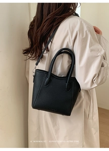 Detail of black lychee grain mini bucket bag on beige coat with a detachable strap