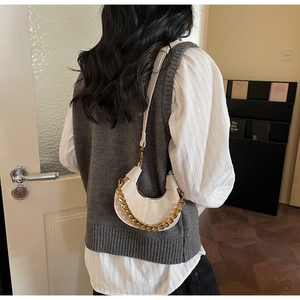 Détail du sac croissant crème en cuir mat avec une grosse chaîne en métal doré
