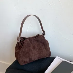 Dettaglio della borsa a mezzaluna in camoscio marrone scuro con pieghe e tracolla regolabile