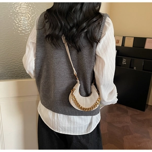 Détail du sac croissant crème avec chaîne dorée et style automnal décontracté