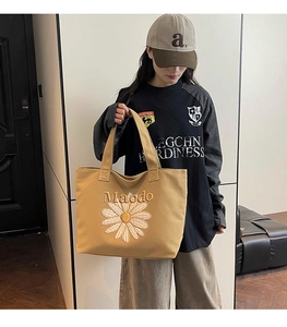 Detailed close-up of embroidered daisy pattern and Maodo logo on canvas tote bag