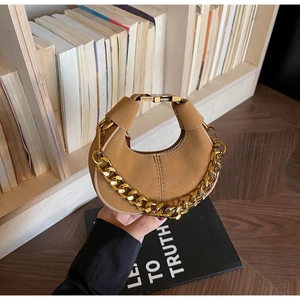Détail d'un sac à main en cuir caramel avec décoration de grosse chaîne dorée