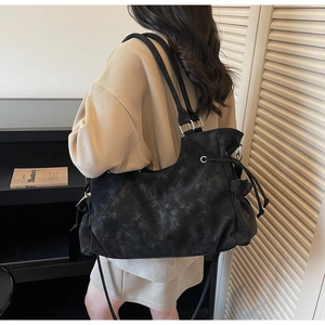 Detail view of large black matte shoulder bag with drawstring texture and silver buckles