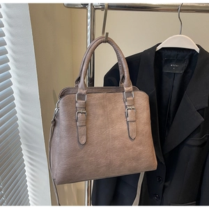 Détail du sac à main vintage en cuir marron avec boucle dorée et bandoulière réglable