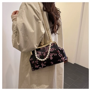 Detail of black shell bag with pink plum blossom embroidery and pearl handle strap