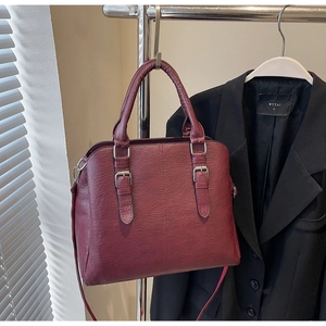 Détail du sac à main bordeaux en similicuir avec grain de litchi et boucles argentées