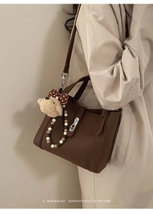 Detail van de donkerbruine leren emmertas met een schattige teddybeer hanger accessoire