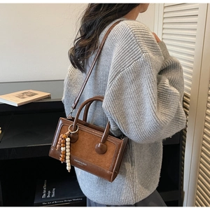 Detail view of retro brown crossbody bag with wooden bead pendant and textured leather mix