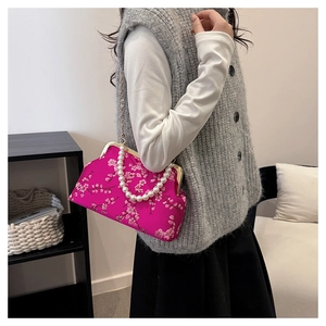Close-up of pink satin evening bag with floral embroidery and pearl handle strap