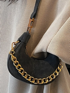 Sac croissant noir minimaliste avec chaîne dorée porté par un mannequin élégant