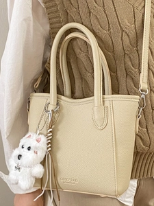 Fashionable beige leather bucket bag with dog pendant shown on model for daily commute