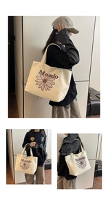 Detail view showing daisy embroidery and Maodo text on a beige canvas tote bag