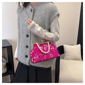 Detail of pink embroidered silk handbag featuring plum blossoms and pearl handle