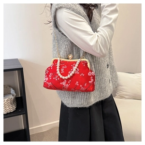 Detail of red Chinese style evening bag with floral embroidery and pearl handle strap