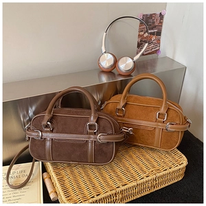 Close-up of vintage suede patchwork boston bags with leather handles on woven tray