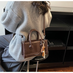 Detail of vintage dark brown crossbody bag with colorful beaded charm and matte leather texture