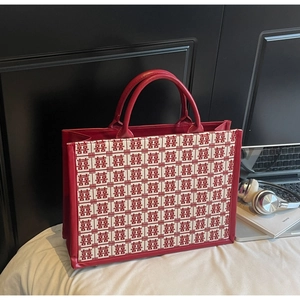 Détail du sac cabas rouge festif montrant le motif traditionnel Xi et les anses en cuir