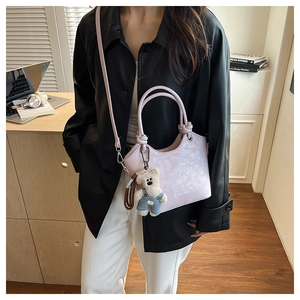 Detail view of light purple leather bucket bag with artistic texture and cute bear pendant