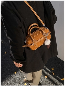 Brown suede crossbody bag shown on person with autumn leaves background and plush charm