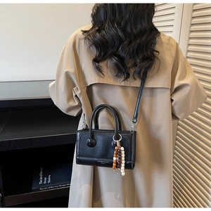 Detail of black leather handbag with decorative beaded tassel and detachable shoulder strap