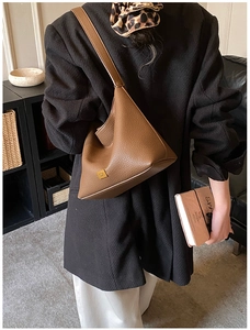 Sac hobo marron en cuir grainé avec logo doré porté à l'épaule par un mannequin