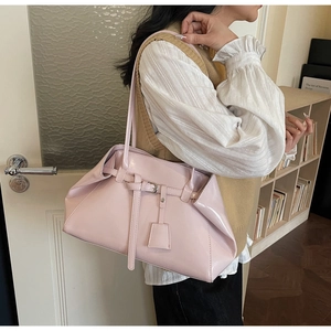 Close-up of pink patent leather tote bag with silver buckle detail on a model