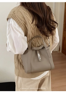 Detailopname van een taupe bucket bag met lychee textuur en zilveren draaisluiting