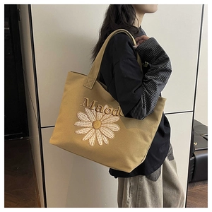 Détail d'un grand sac cabas en toile kaki avec broderie de marguerite blanche et texte Maode
