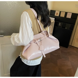 Model wearing a large pink patent leather tote bag with silver buckle in a warm interior