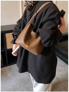Détail du sac seau en cuir marron grainé avec une plaque décorative en métal doré élégant