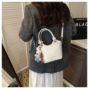 Minimalist white leather bucket bag with top handle and cute blue bear plush pendant