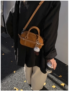 Brown suede crossbody bag with plush charm shown in an autumn street setting