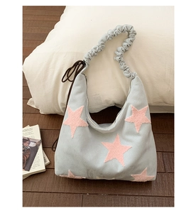 Close-up of fluffy pink stars on a light blue pleated shoulder bag for daily use