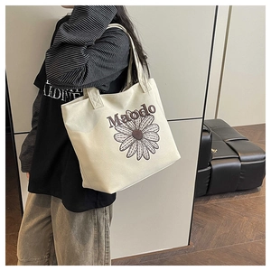 Détail du sac fourre-tout en toile beige avec lettrage Maodo et broderie marguerite