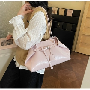 Detail view of pink glossy faux leather tote bag with decorative buckle and square charm