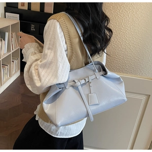 Close-up of light blue shoulder tote bag with glossy finish and decorative strap buckle