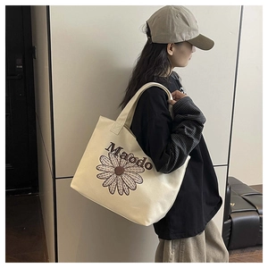 Gros plan sur un grand sac cabas en toile beige avec broderie marguerite et logo Maodo