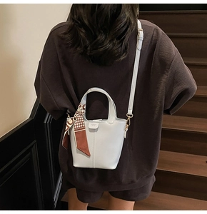 Rear view of a light blue bucket bag with a decorative silk scarf and crossbody strap