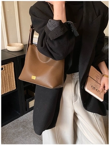 Vue détaillée du cuir marron foncé à motif lychee et du logo en métal doré du sac hobo
