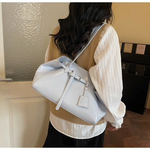 Detail of glossy light blue tote bag featuring polished finish and decorative strap charm