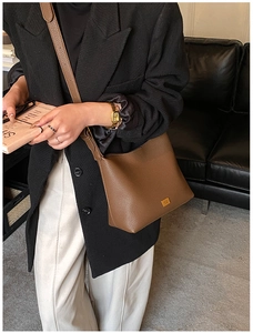 Détail d'un sac hobo en cuir grainé marron foncé avec finitions dorées et bandoulière