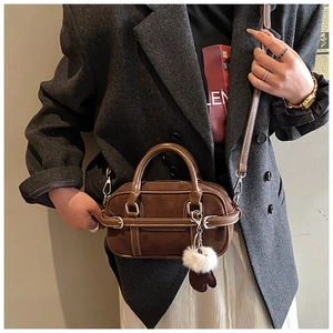 Brown suede crossbody bag detail with metallic buckle and soft plush glove charm