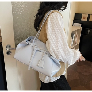 Detailed close-up of a light blue faux leather tote bag with elegant metal buckle and tag