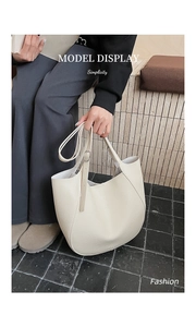 Detail view of large cream tote bag showing soft lychee texture leather being held by a model