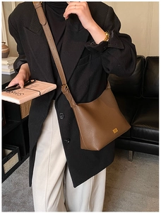 Détail d'un sac seau en cuir marron à motif litchi avec une large bandoulière réglable