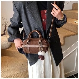 Detail of dark brown suede Boston bag with leather straps and plush glove charm