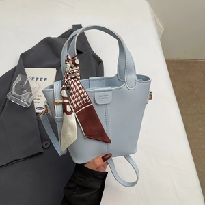 Detail of light blue bucket bag with houndstooth silk scarf and fashion closure