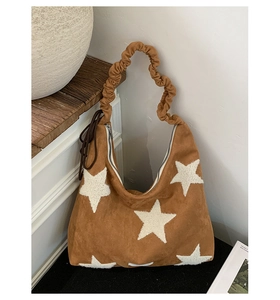 Detail of brown suede tote bag with white plush star pattern and ruched handles